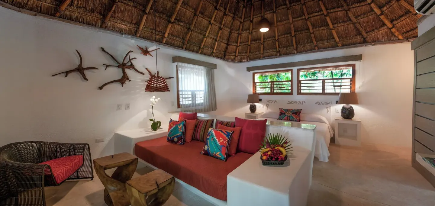 Guest room with king bed and red daybed seating at Mahekal Beach Front Resort & Spa.