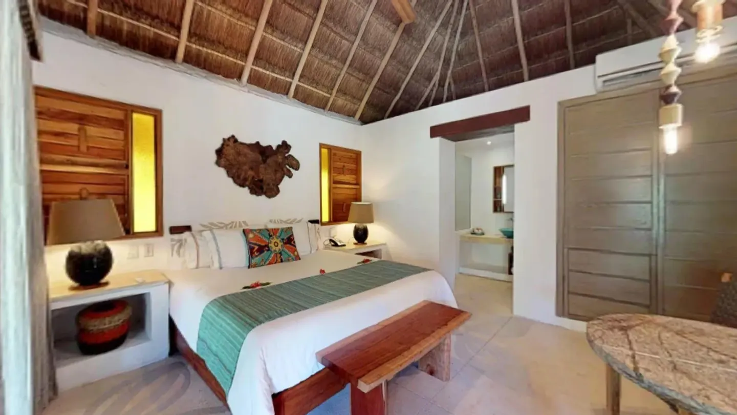 Guest room with king bed and thatched ceiling at Mahekal Beach Front Resort & Spa.