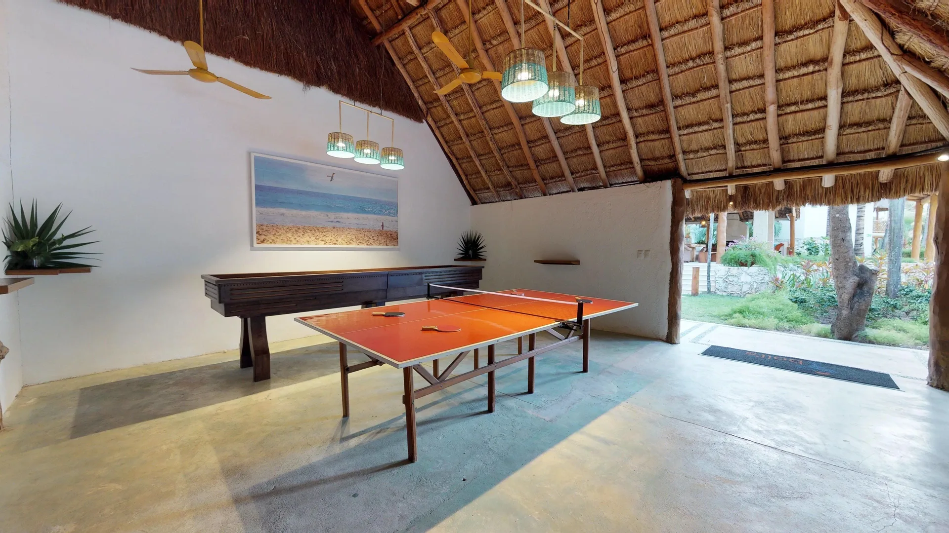 Indoor ping-pong table beneath a thatched roof at Mahekal Beach Front Resort & Spa.