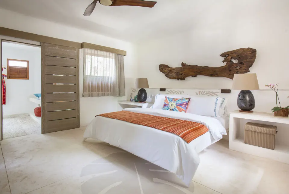 Bright guest room with king bed and driftwood wall art at Mahekal Beach Front Resort & Spa