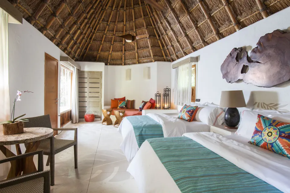 Spacious palapa-roof guest room with two beds at Mahekal Beach Front Resort & Spa