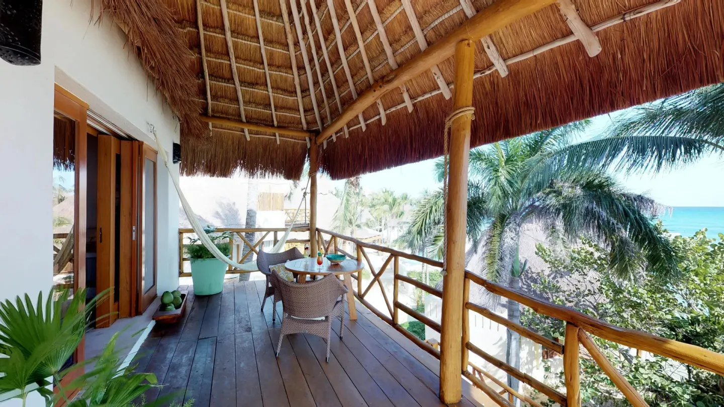 Thatched guest terrace with hammock and ocean view at Mahekal Beach Front Resort & Spa.