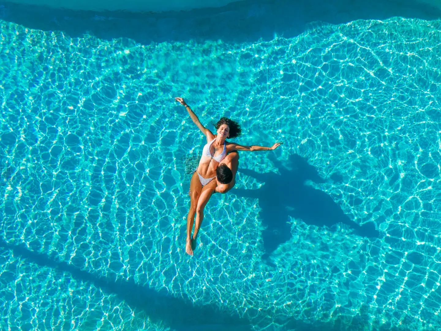 Swimmer floating in a bright blue pool at Mahekal Beach Front Resort & Spa.