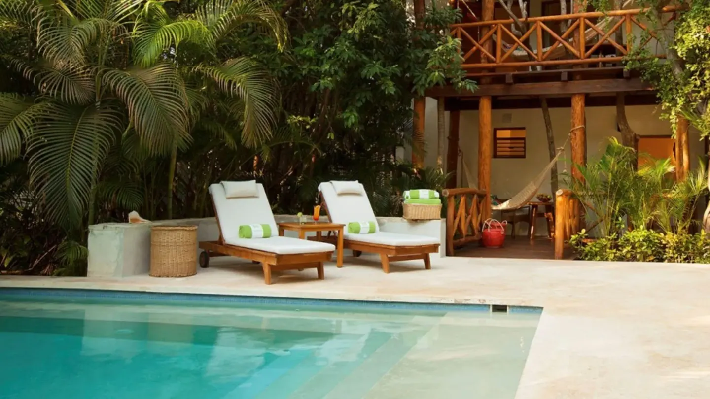Poolside loungers and a hammock beside a casita at Mahekal Beach Front Resort & Spa.