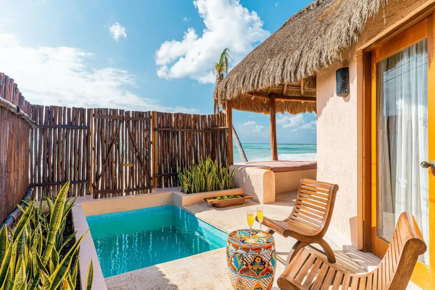 Private plunge pool patio beside a thatched guest room at Mahekal Beach Front Resort & Spa.