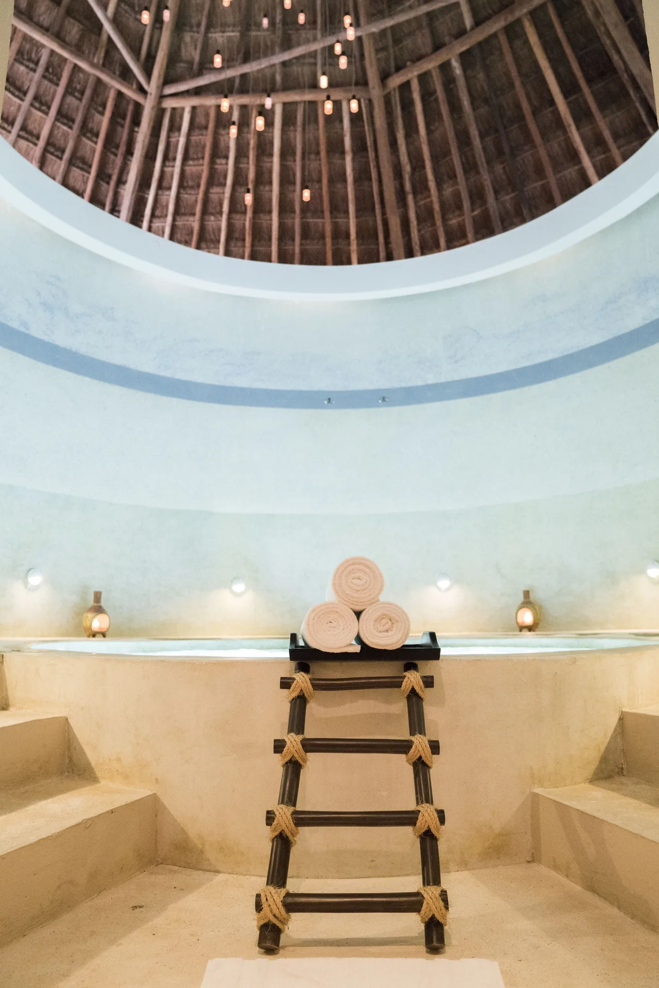 Spa soaking area with rolled towels under a high palapa roof at Mahekal Beach Front Resort & Spa.