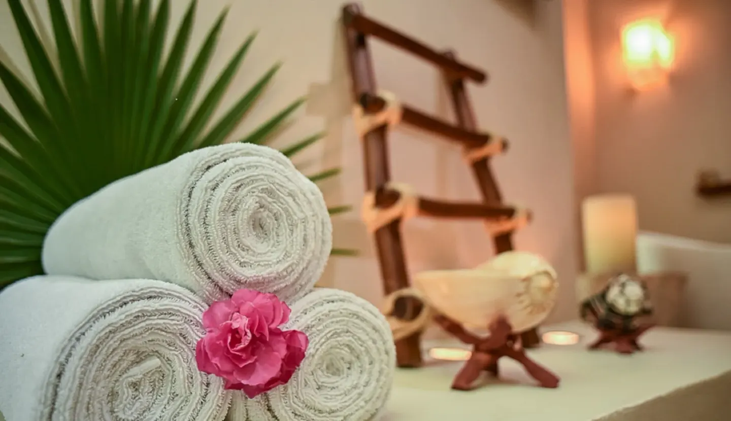 Rolled spa towels with a pink flower at Mahekal Beach Front Resort & Spa.