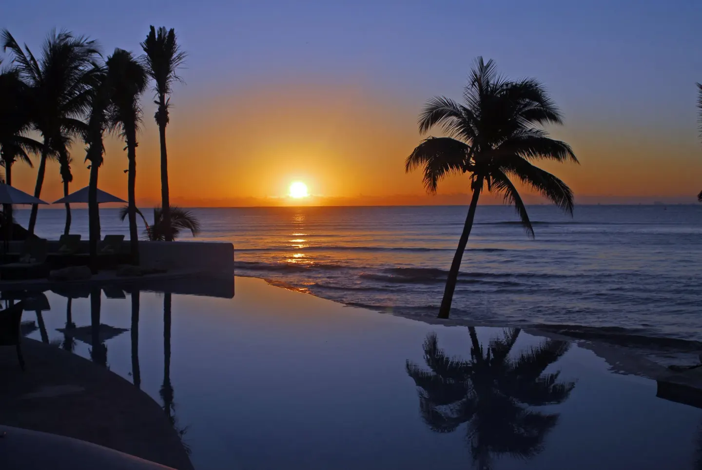Sunset over the ocean and pool at Mahekal Beach Front Resort & Spa.