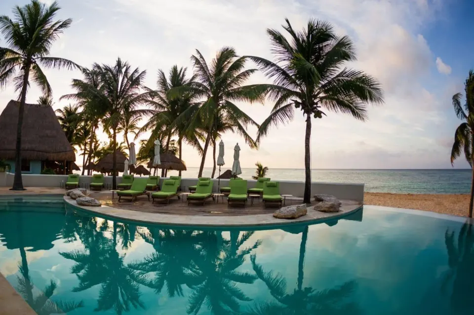 Sunset reflections in the pool with palm silhouettes at Mahekal Beach Front Resort & Spa