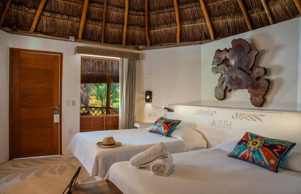 Guest room with twin beds, rolled towels, and balcony at Mahekal Beach Front Resort & Spa