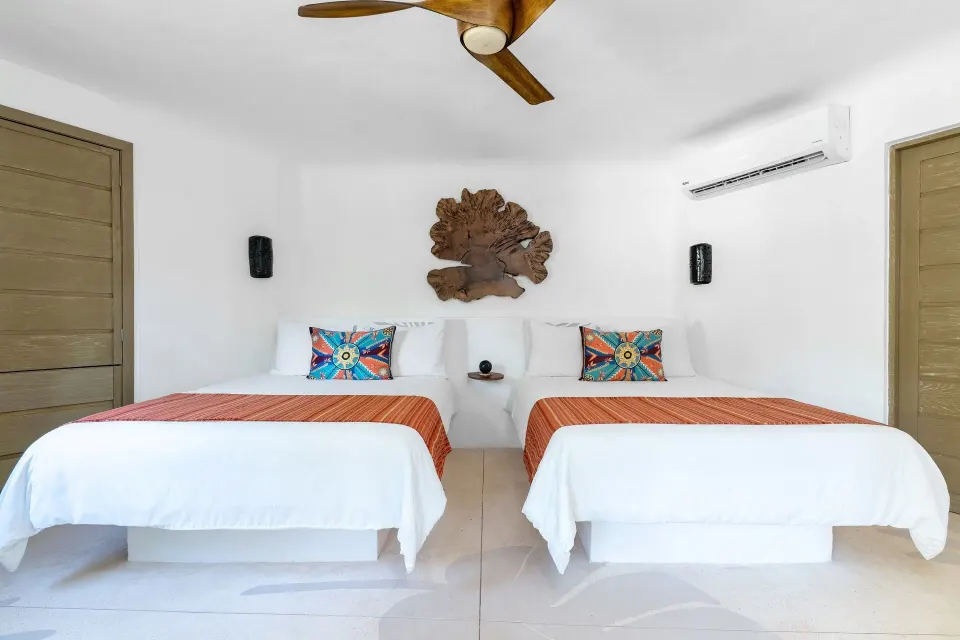 Twin beds with colorful pillows in a bright guest room at Mahekal Beach Front Resort & Spa