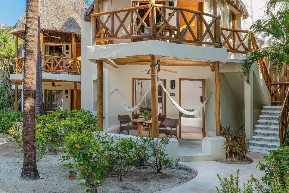 Exterior of two-story bungalow with ground-level hammock at Mahekal Beach Front Resort & Spa