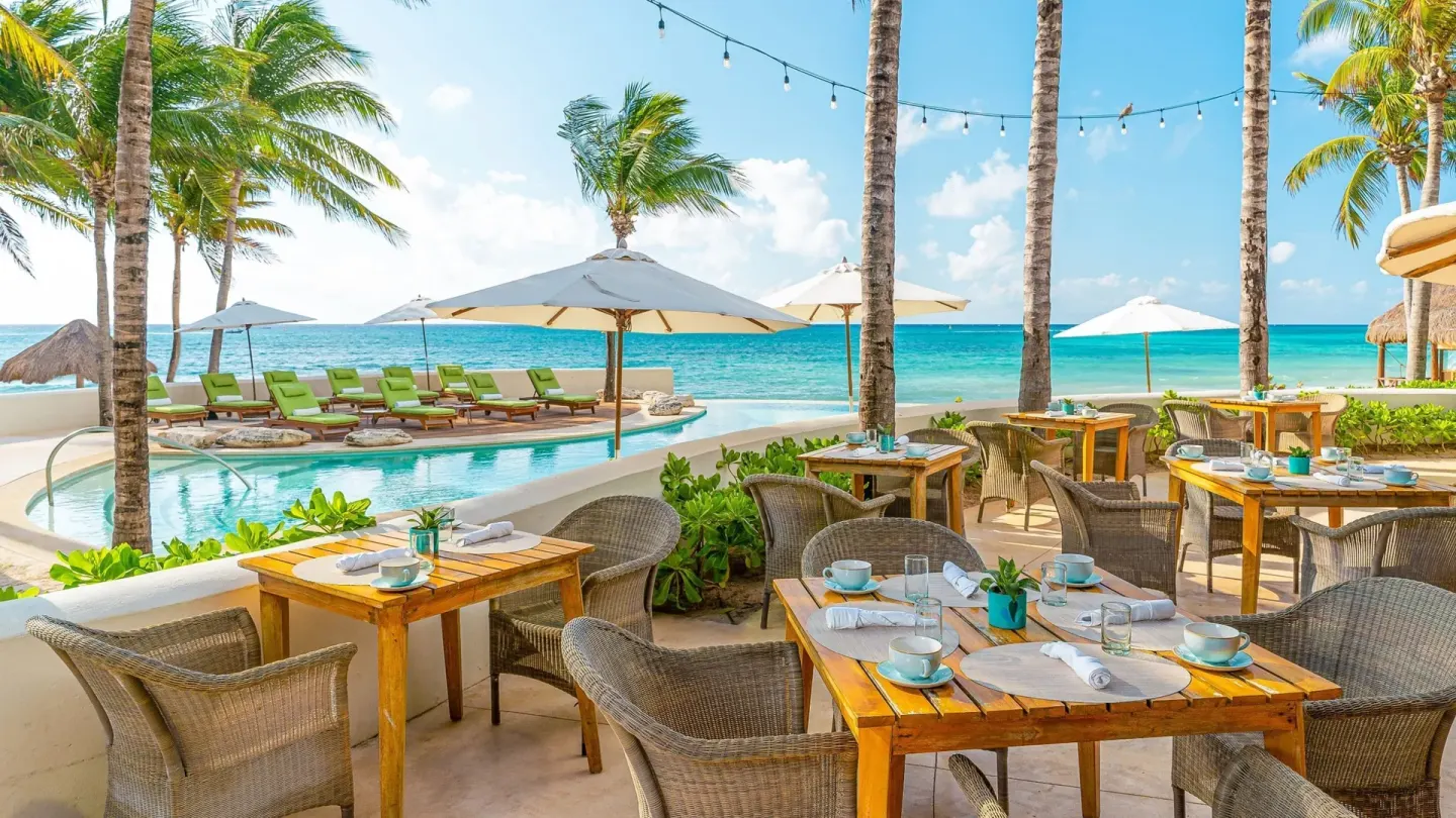 Oceanfront dining tables beside the pool and beach at Mahekal Beach Front Resort & Spa.