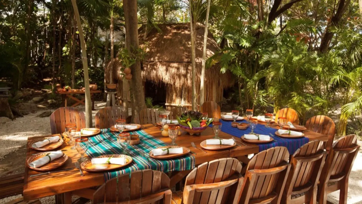 Outdoor wooden dining table set in the jungle at Mahekal Beach Front Resort & Spa.