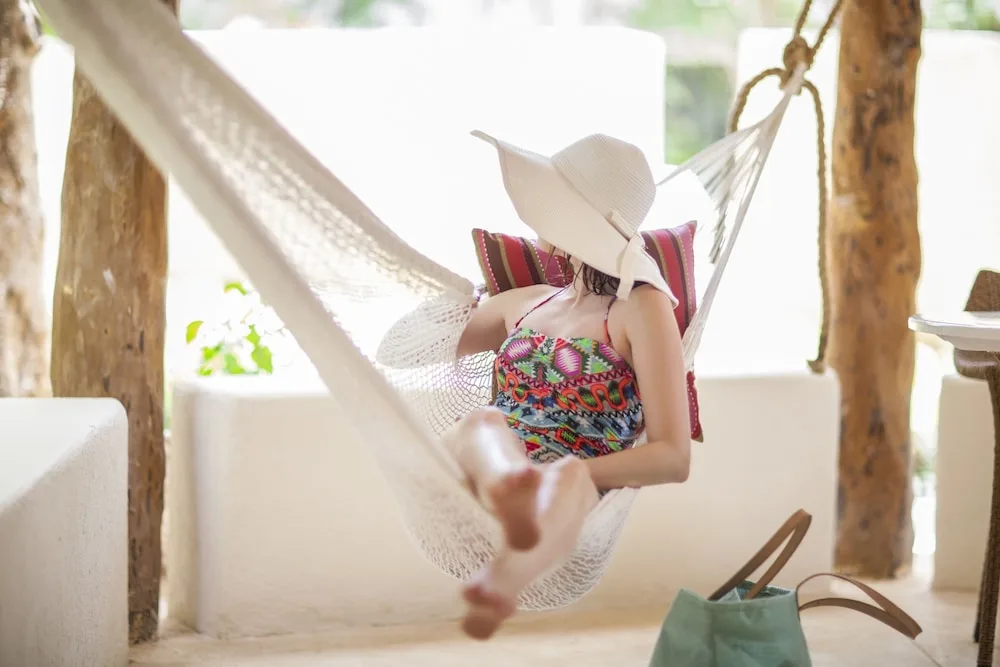 Guest relaxing in a patio hammock outside a Garden View room at Mahekal Beach Front Resort & Spa.