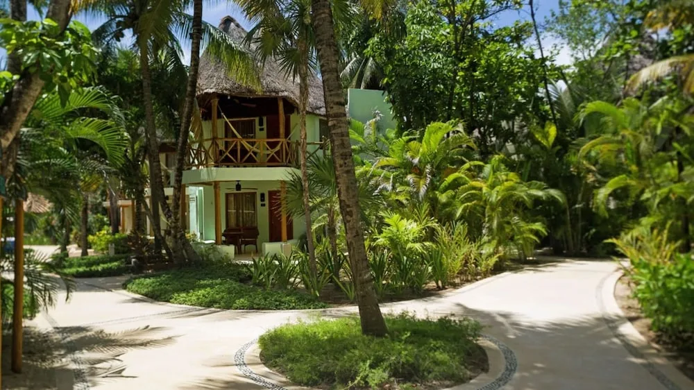 Garden View room building amid palms and curving paths at Mahekal Beach Front Resort & Spa.