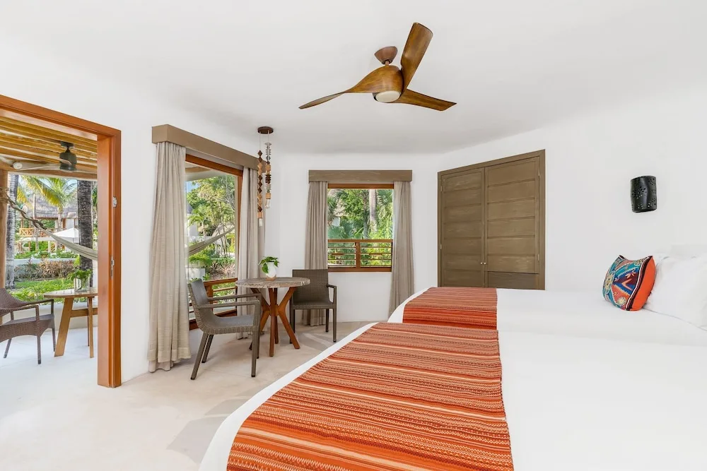 Garden View room with king bed, table, windows and terrace at Mahekal Beach Front Resort & Spa.