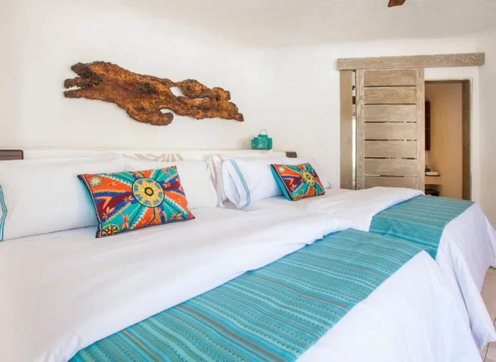 Garden View double beds with turquoise runners at Mahekal Beach Front Resort & Spa.
