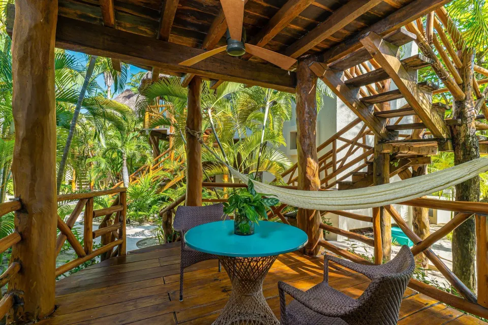 Private wooden terrace with hammock and seating in a Garden View Room at Mahekal Beach Front Resort & Spa