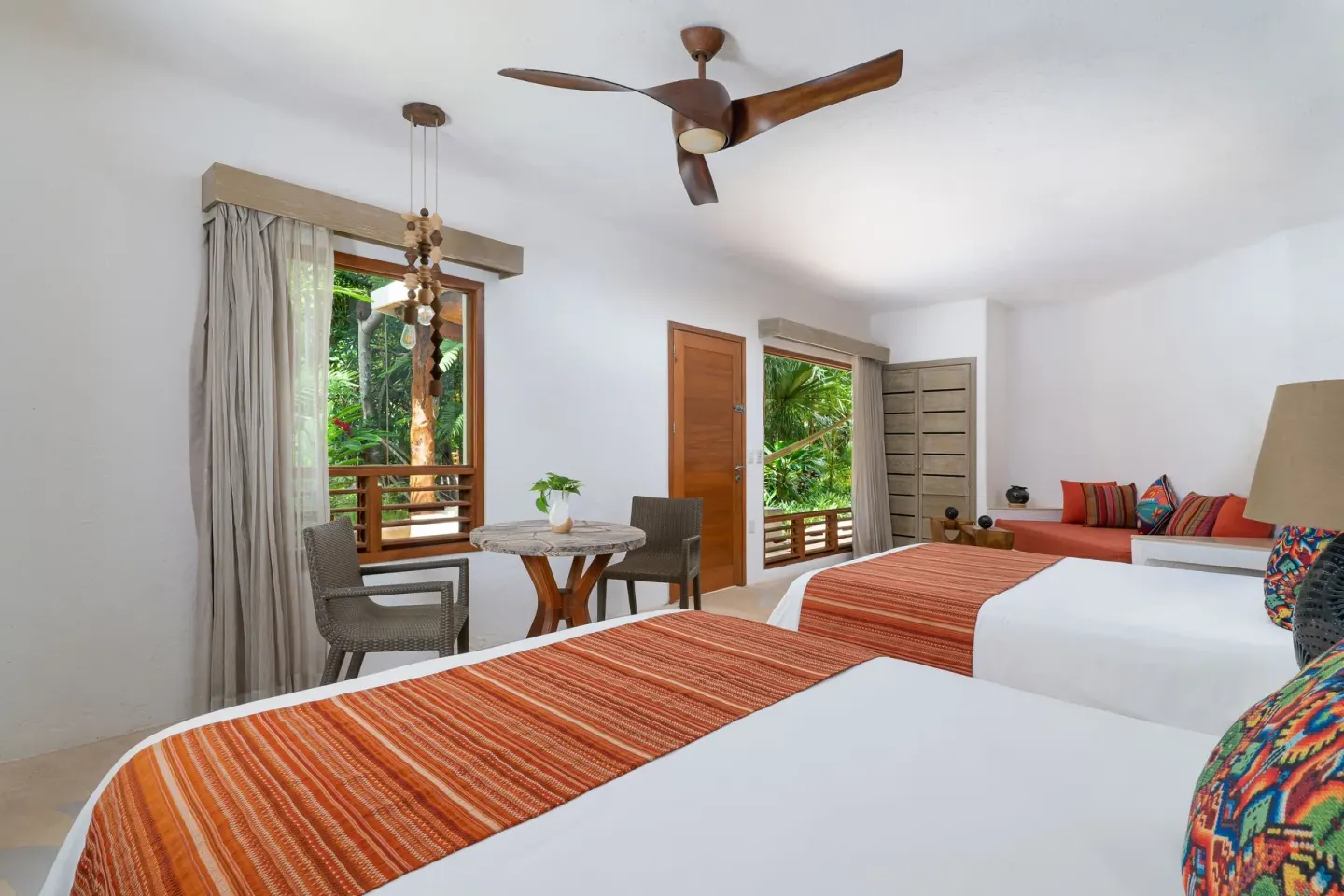 Garden View room with two beds, orange runners, and leafy window views at Mahekal Beach Front Resort & Spa.