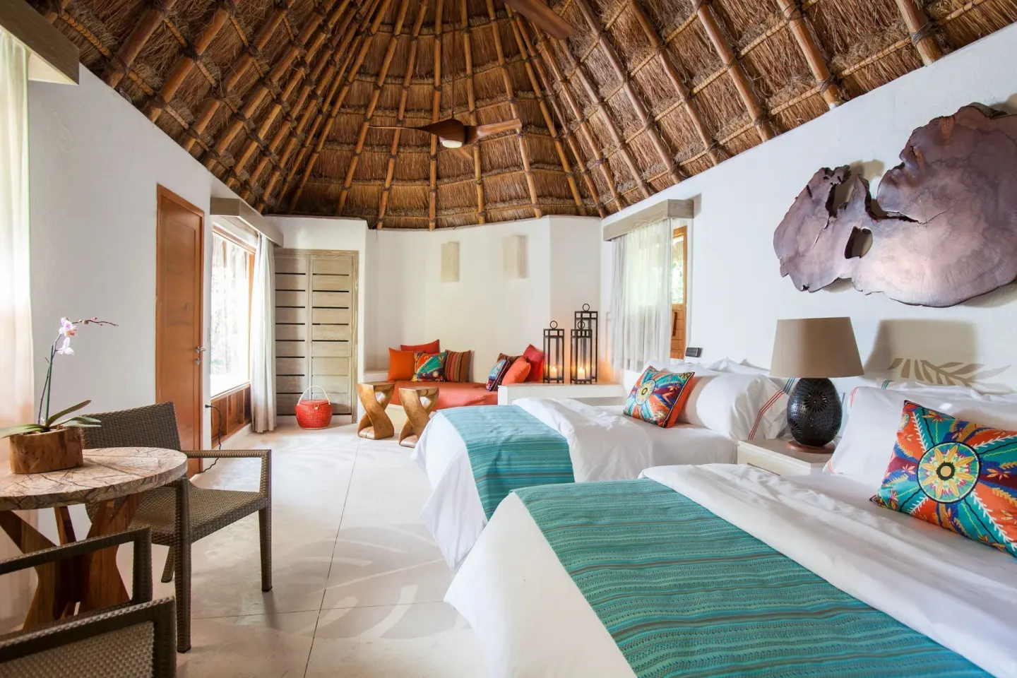 Garden View room with two beds, sitting area, and tall thatched ceiling at Mahekal Beach Front Resort & Spa.