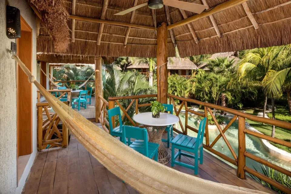 Thatched balcony with hammock and turquoise chairs overlooking gardens at Mahekal Beach Front Resort & Spa
