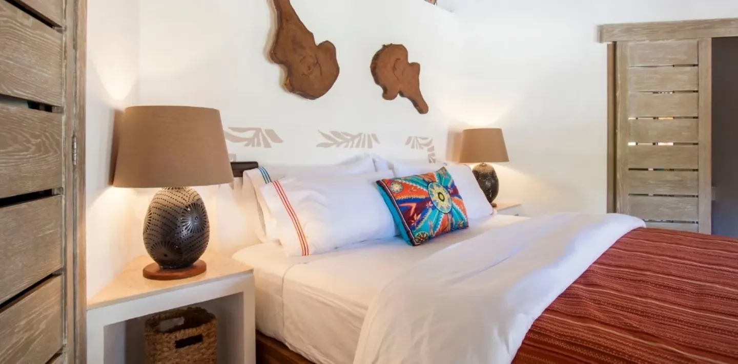 Run of House king bed with lamps and carved wood decor at Mahekal Beach Front Resort & Spa.