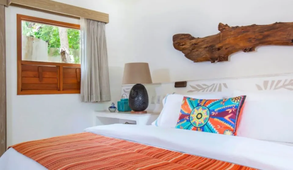 Run of House king bed beside a shuttered window at Mahekal Beach Front Resort & Spa.