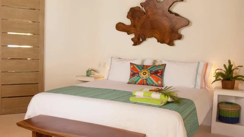 King bed with green runner and driftwood wall art in a Run of House room at Mahekal Beach Front Resort & Spa