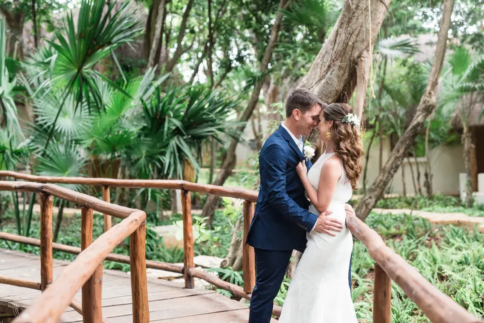 Bride and groom embracing on a wooden garden bridge at Mahekal Beach Front Resort & Spa