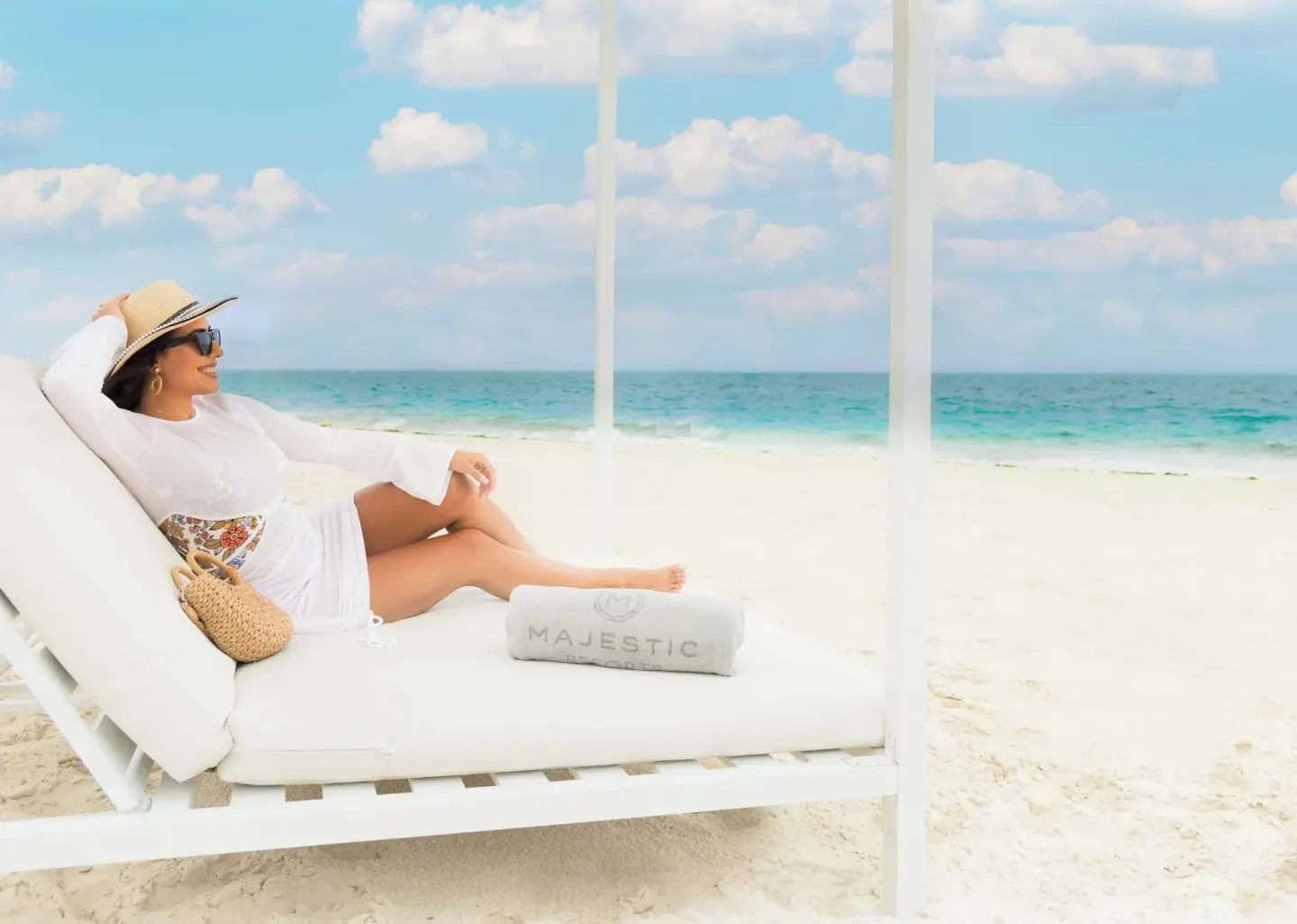 Guest reclining on a white beach daybed at Majestic Elegance Costa Mujeres.
