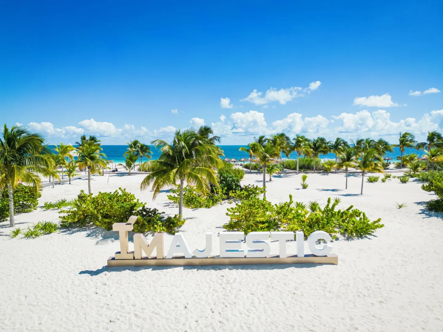 White sand beach with Majestic sign at Majestic Elegance Costa Mujeres.