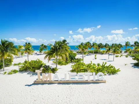 White sand beach with Majestic sign at Majestic Elegance Costa Mujeres.