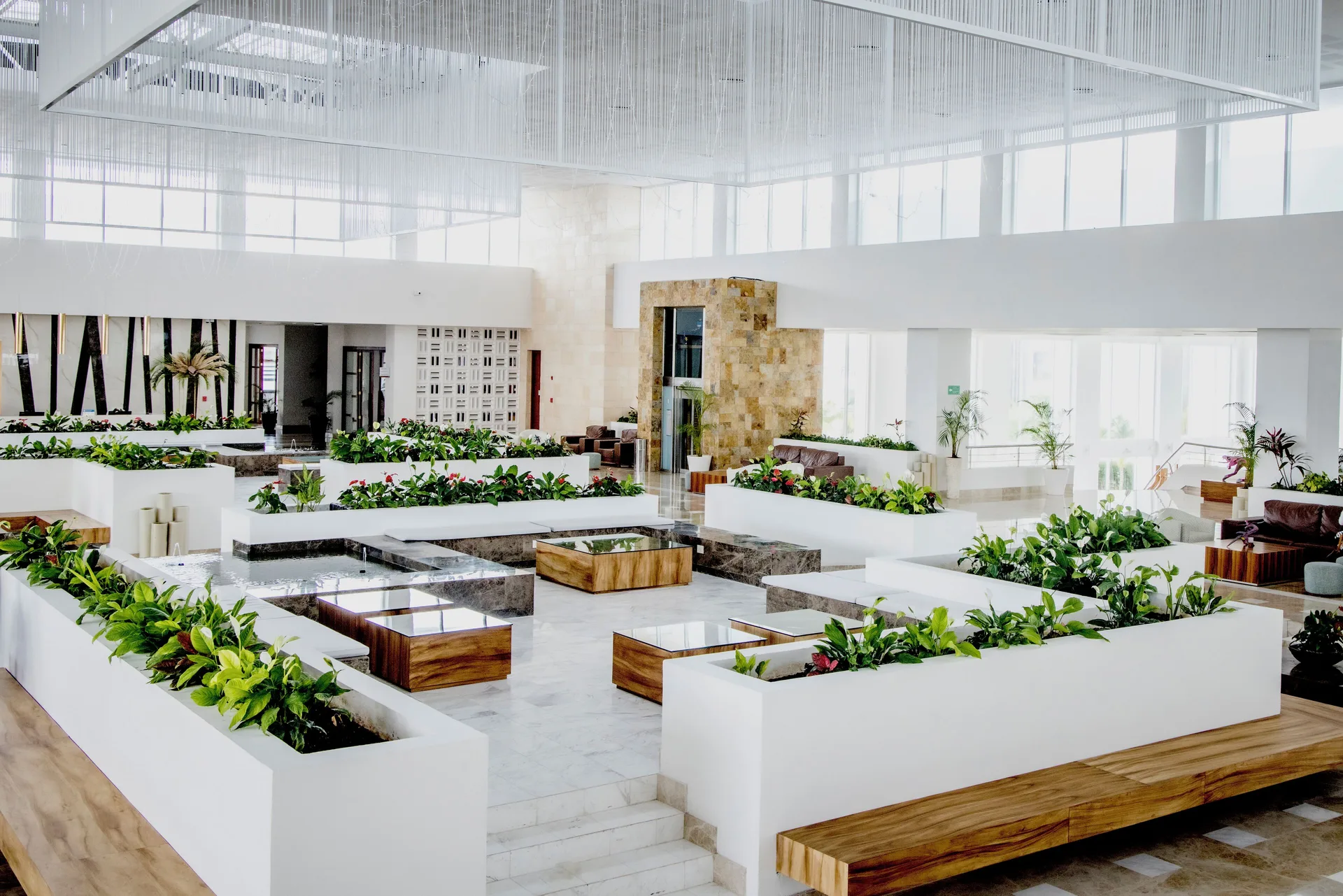 Bright lobby with white planters and lounge seating at Majestic Elegance Costa Mujeres.