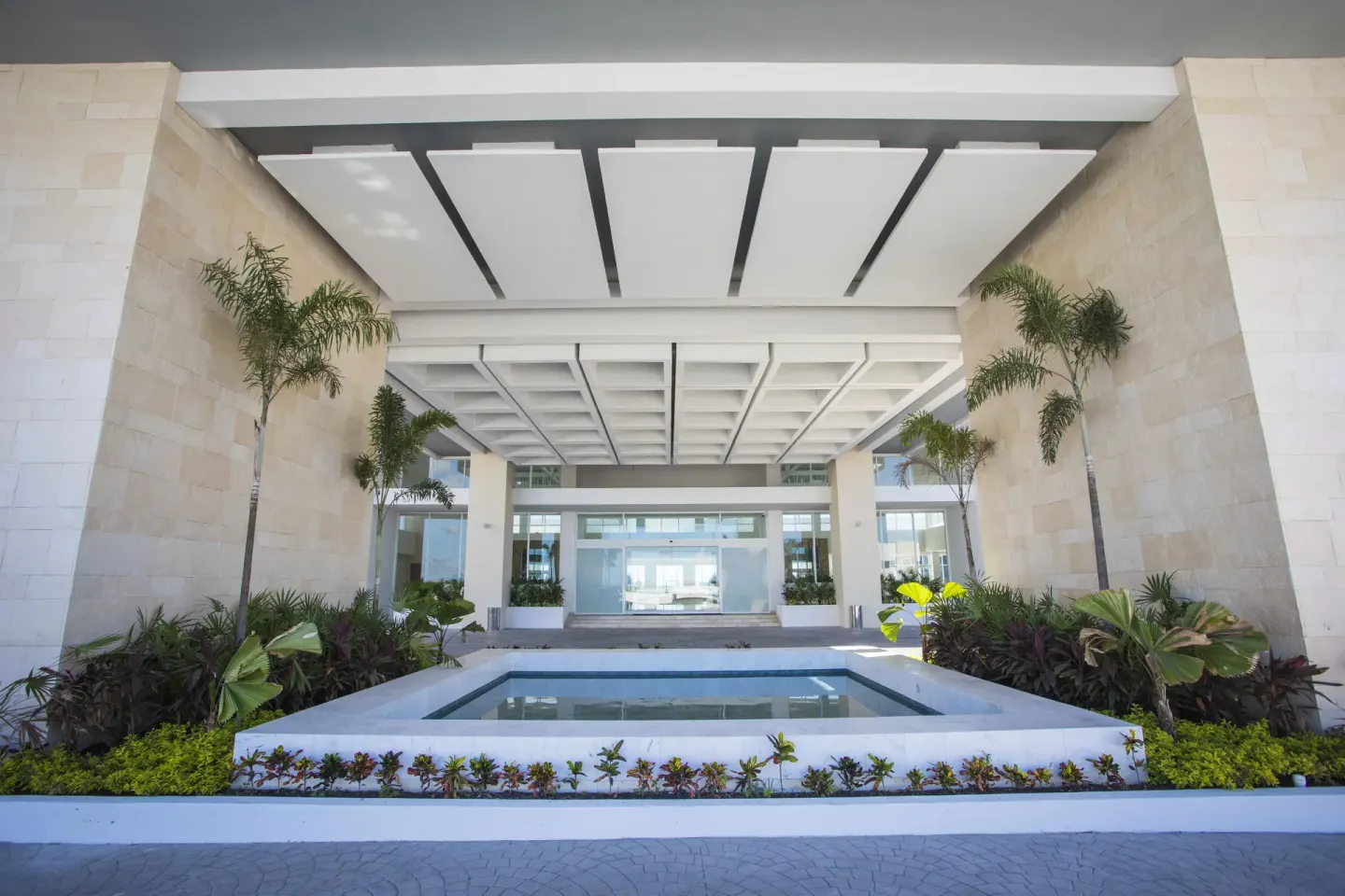 Covered entrance with reflecting pool and palms at Majestic Elegance Costa Mujeres.
