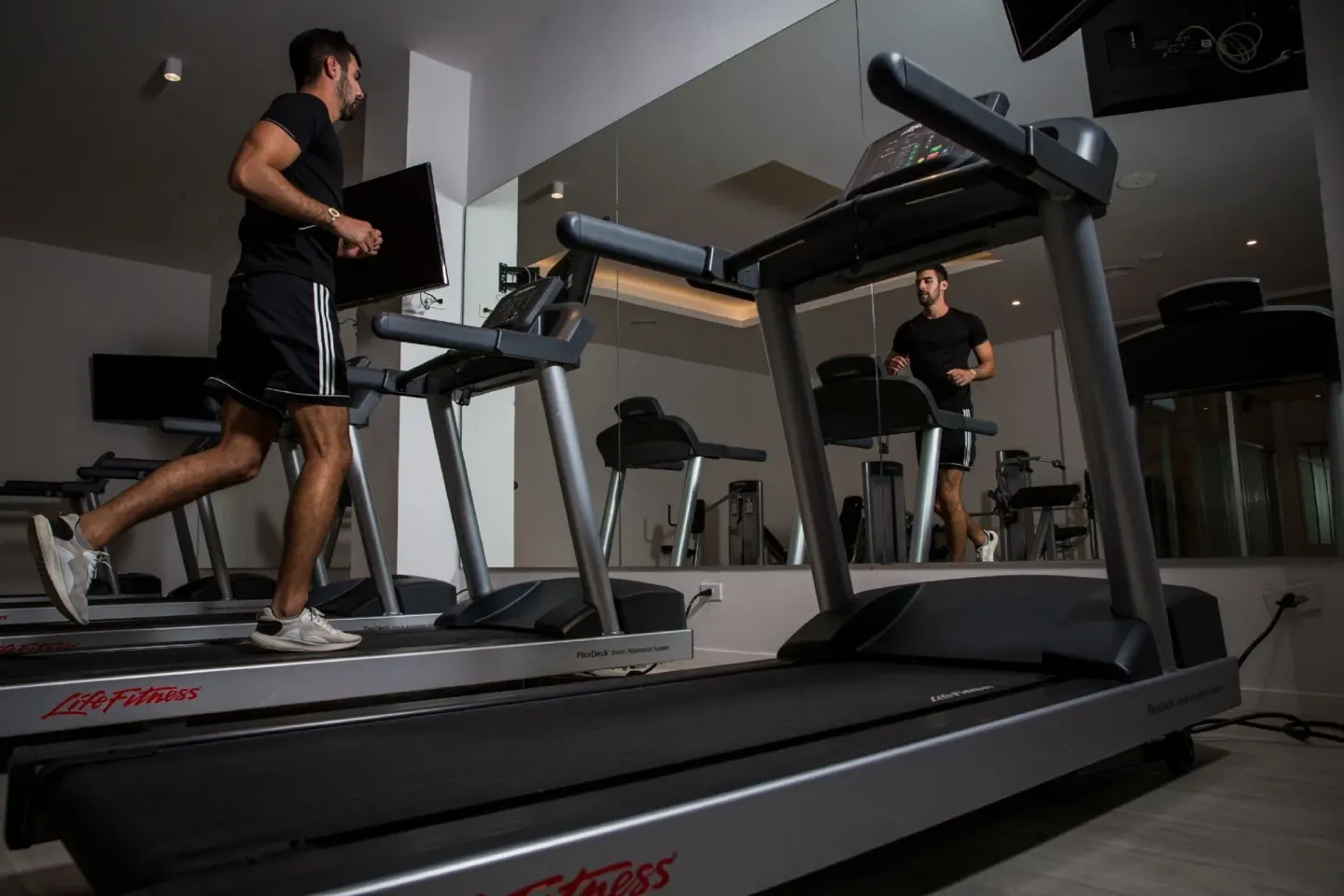 Fitness room with treadmills and mirrored wall at Majestic Elegance Costa Mujeres.
