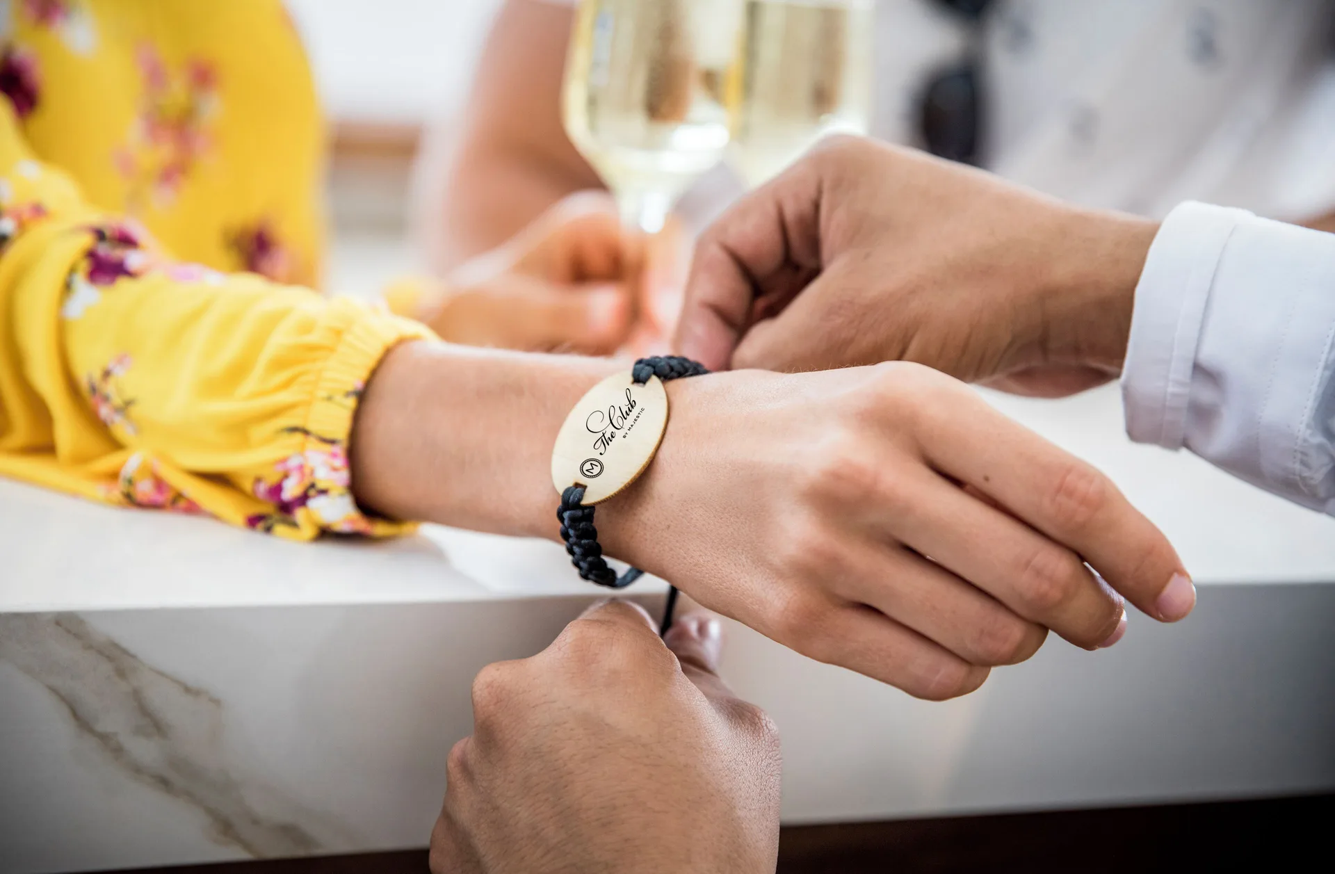 A staff member fastens a guest bracelet at Majestic Elegance Costa Mujeres.