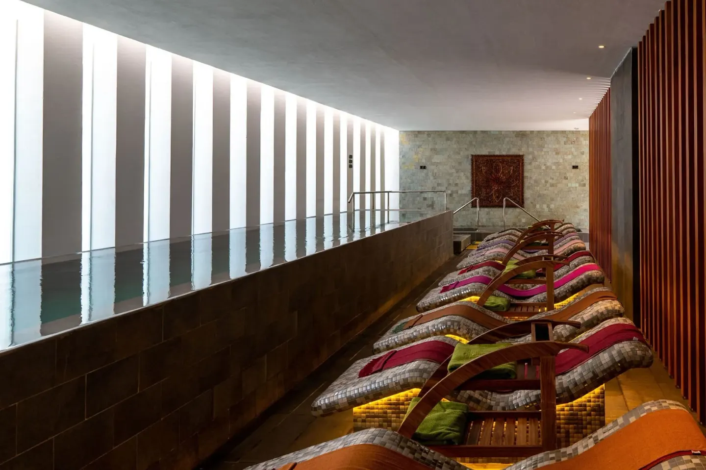 Indoor spa pool with cushioned loungers at Majestic Elegance Costa Mujeres.