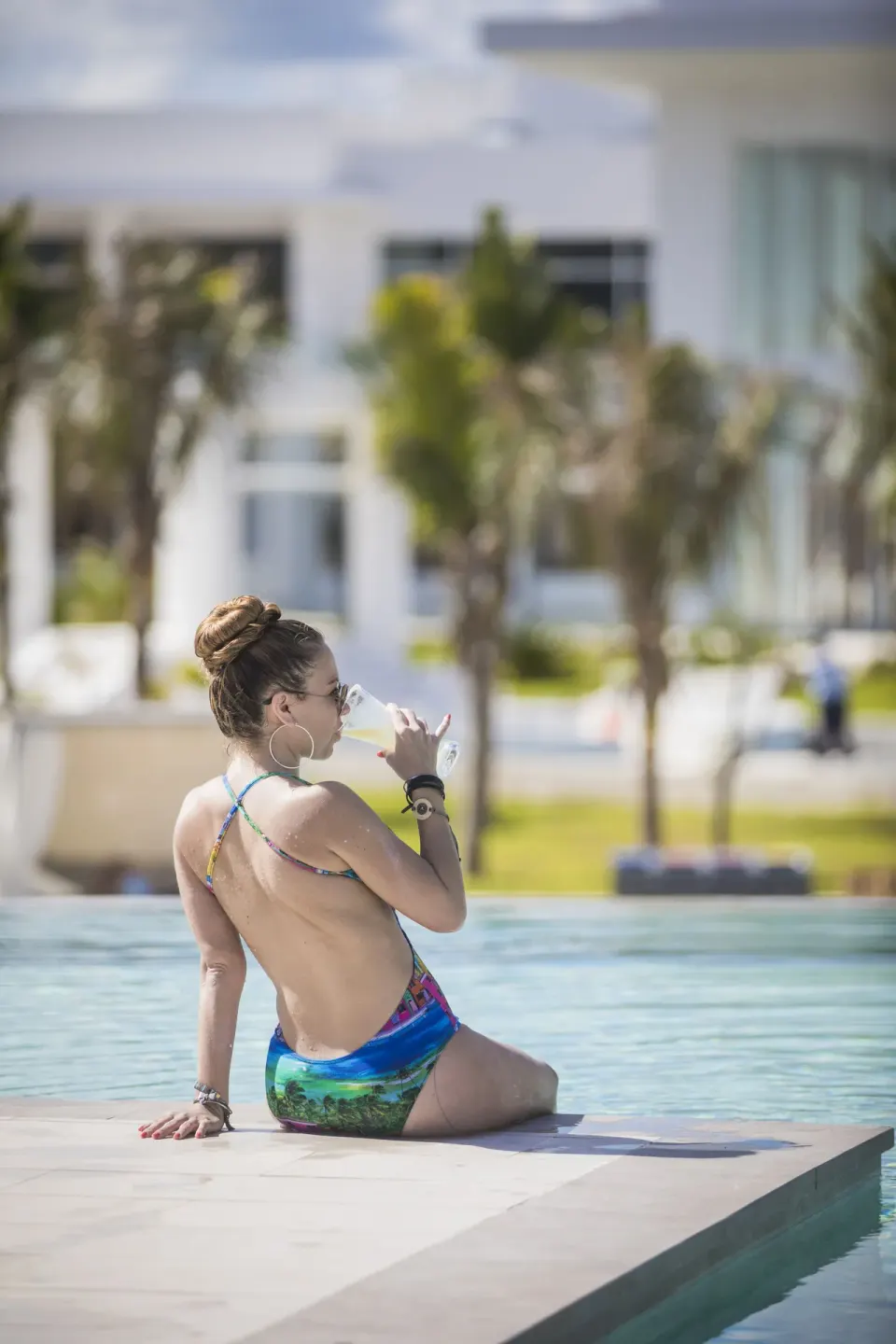 Guest sitting at the edge of a resort pool at Majestic Elegance Costa Mujeres.