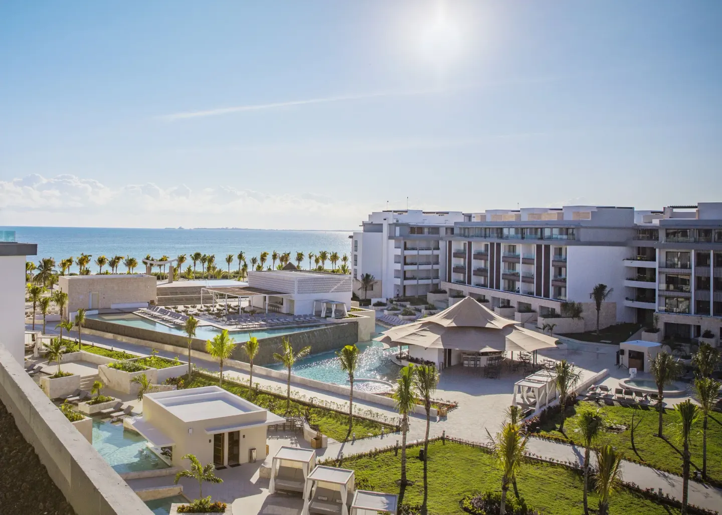 Aerial resort view with pools, palms, and ocean at Majestic Elegance Costa Mujeres.