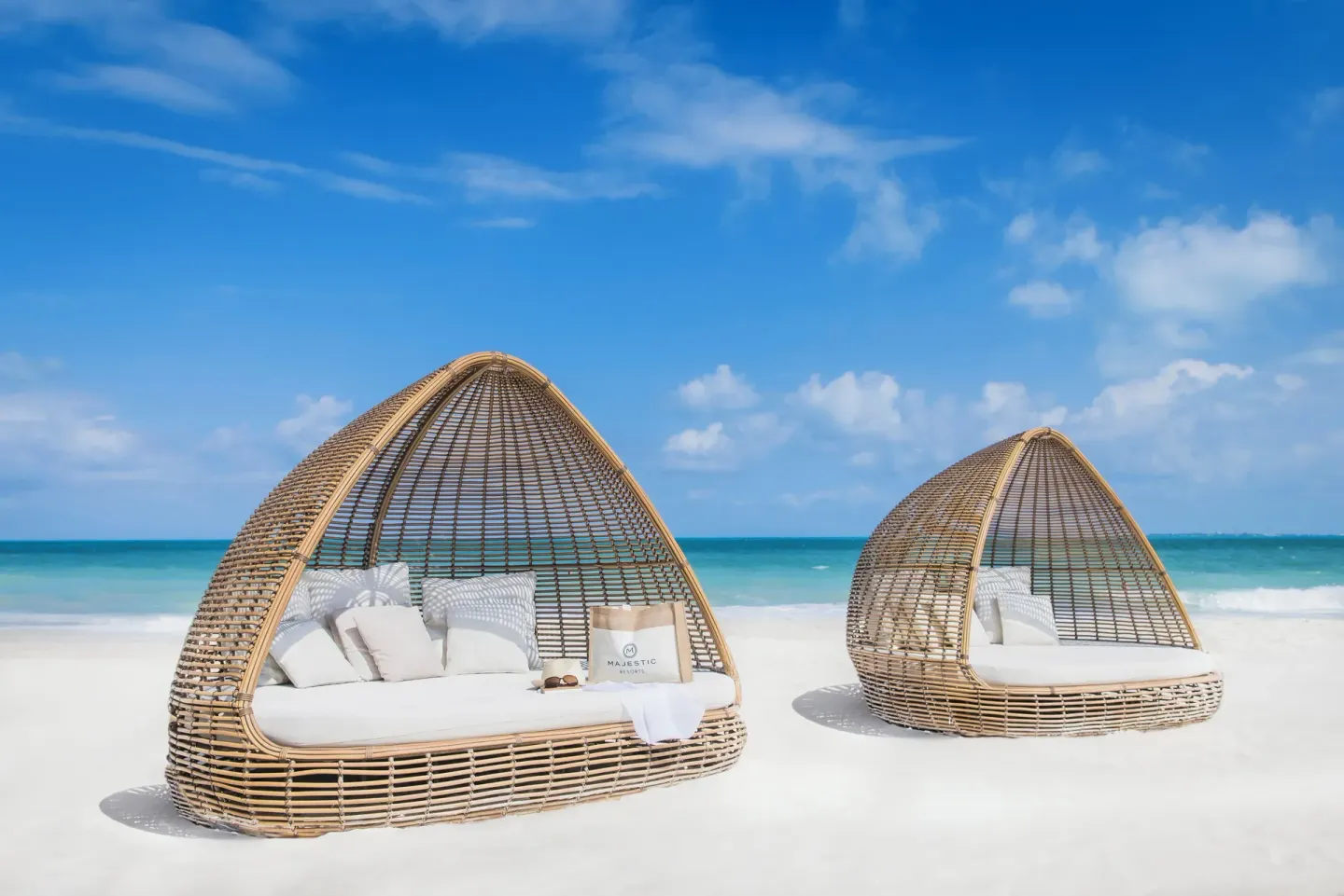 Woven beach cabanas with white cushions at Majestic Elegance Costa Mujeres.