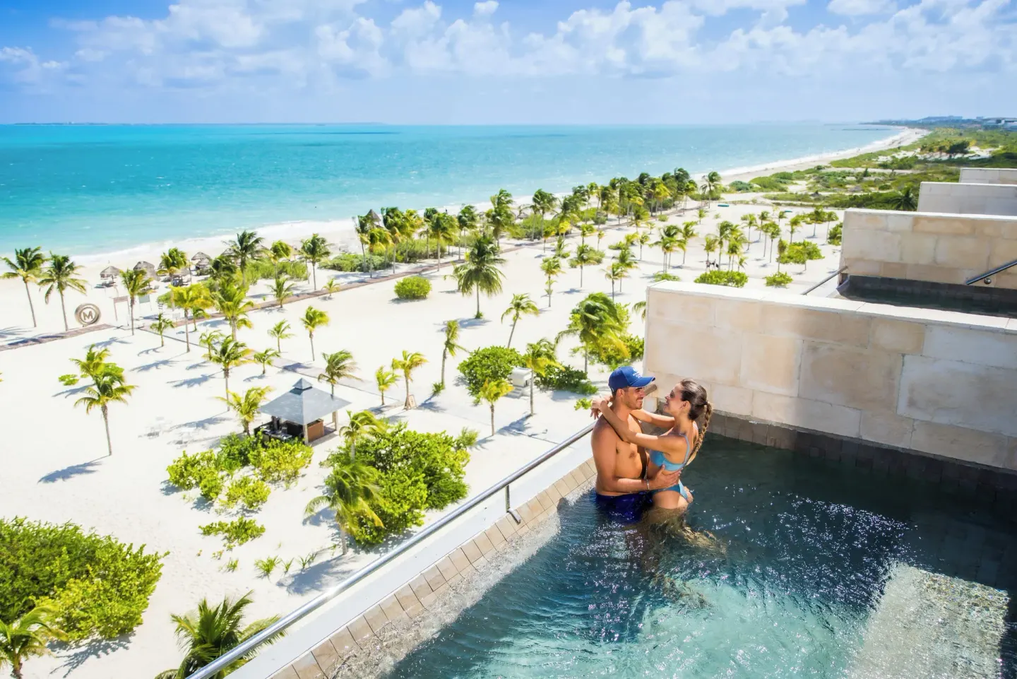 Oceanfront plunge pool at Majestic Elegance Costa Mujeres with couple and panoramic beach view.