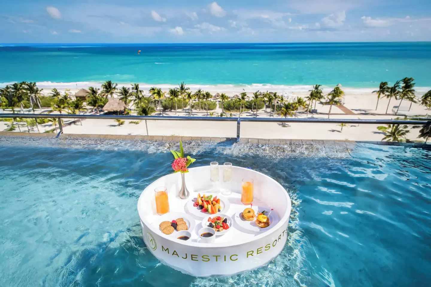 Floating breakfast in an oceanfront plunge pool at Majestic Elegance Costa Mujeres above the beach.
