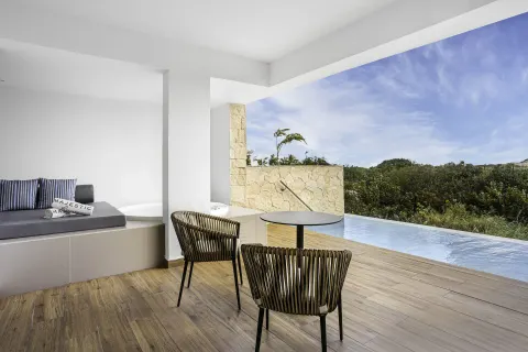 Covered swim-up suite terrace facing greenery at Majestic Elegance Costa Mujeres.
