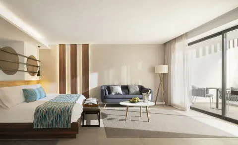 Junior Suite bedroom and sitting area at Majestic Elegance Costa Mujeres with balcony doors.