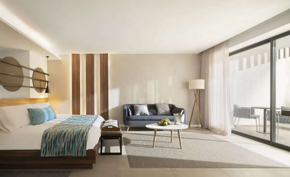 Junior Suite bedroom and sitting area at Majestic Elegance Costa Mujeres with balcony doors.