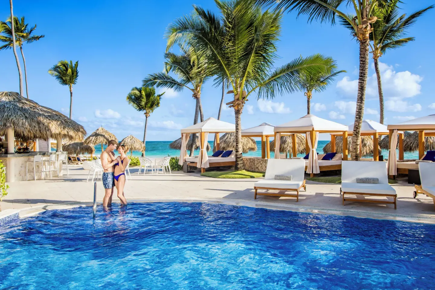 Beachside pool with cabanas and palm trees at Majestic Elegance Punta Cana.
