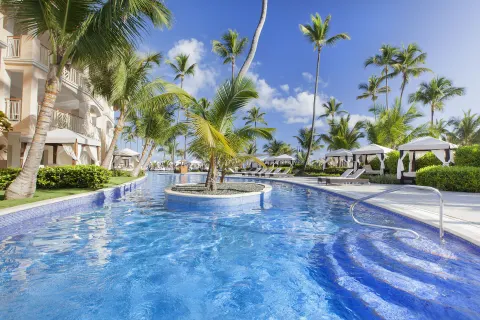 Curving pool with palm island and cabanas at Majestic Elegance Punta Cana.