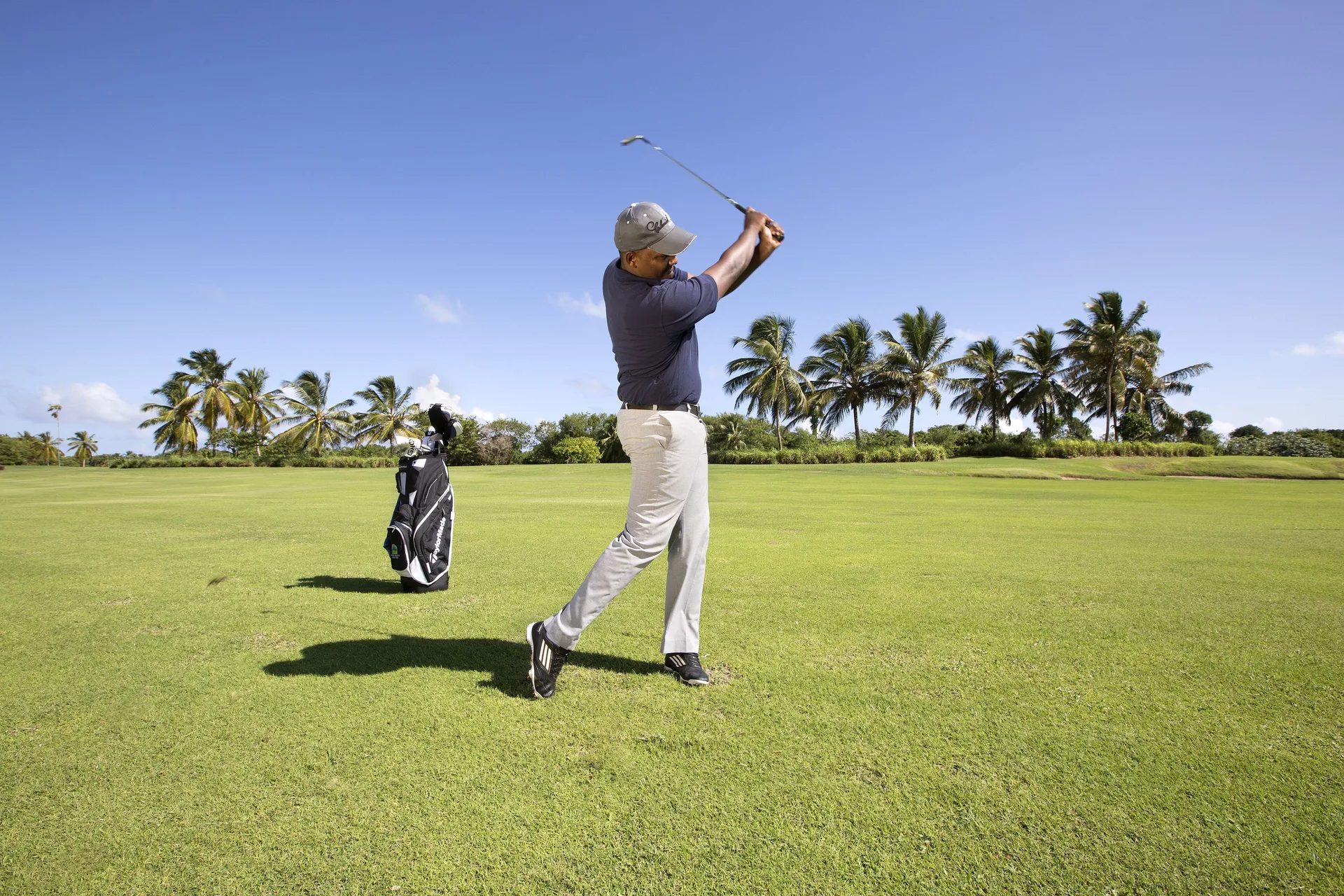 Golfer following through on a palm-lined course near Majestic Elegance Punta Cana.