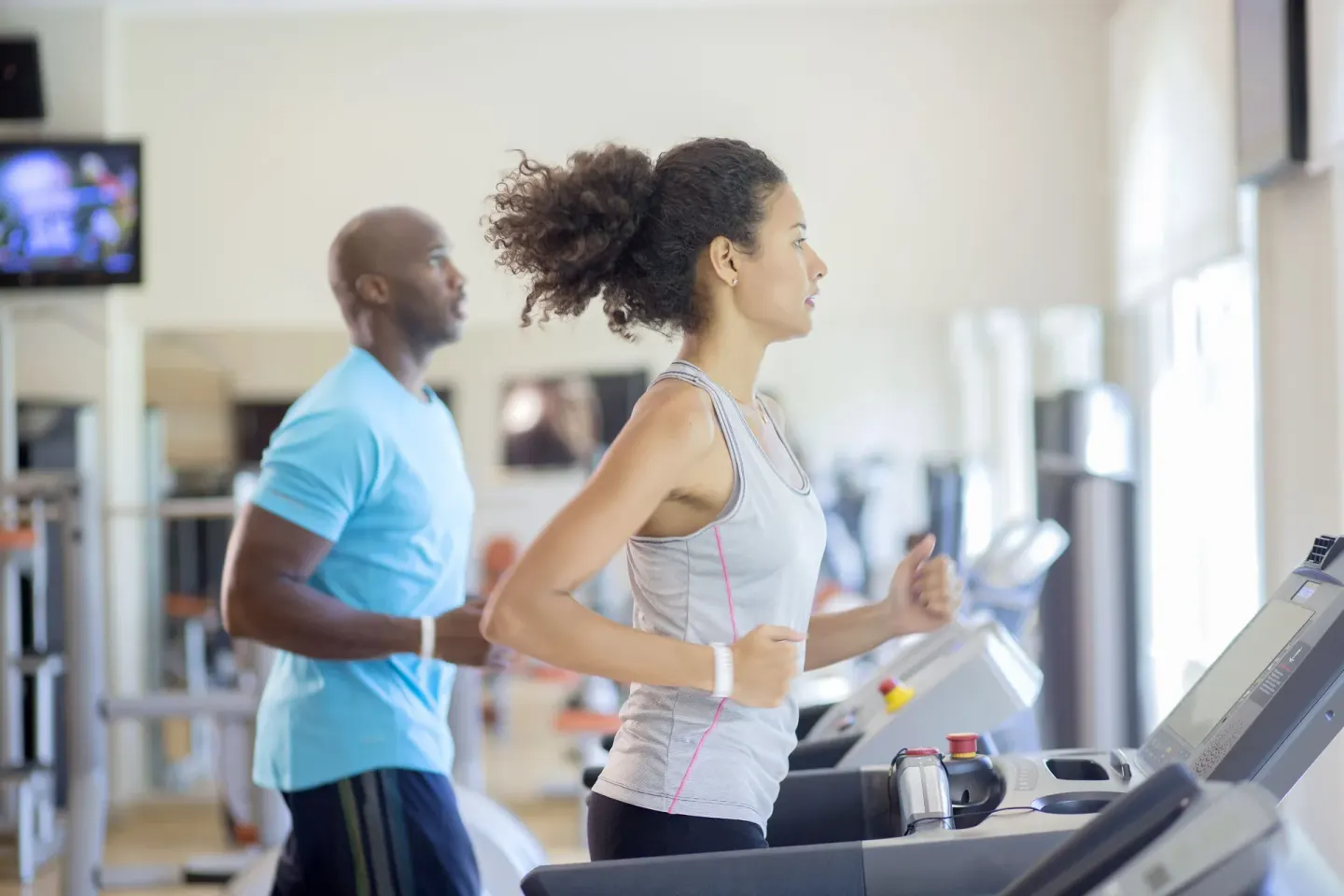 Two guests jog on treadmills in the gym at Majestic Elegance Punta Cana.